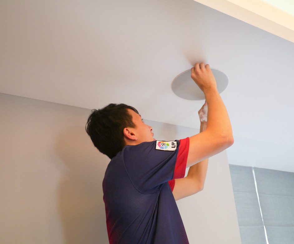 Technician installing a flush-mount ceiling speaker